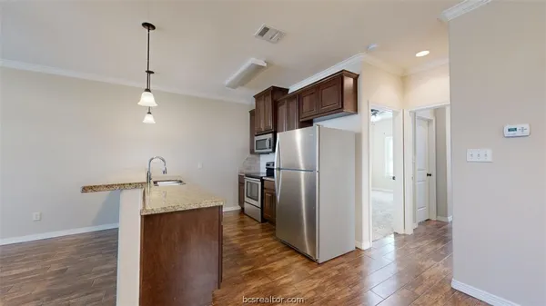 a view of a kitchen with refrigerator and wooden floor