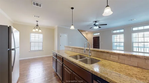 a kitchen with stainless steel appliances granite countertop a sink a refrigerator and a chandelier
