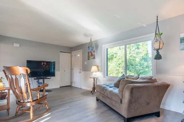 a living room with furniture a flat screen tv and a large window