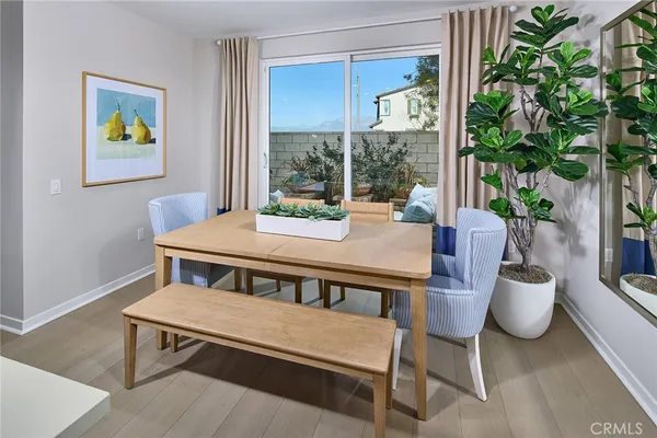 a view of a dining room with furniture a potted plant and a window