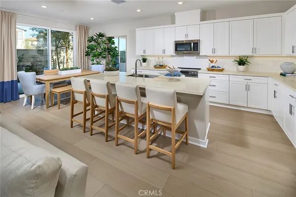 a kitchen with stainless steel appliances kitchen island granite countertop a table chairs sink and cabinets