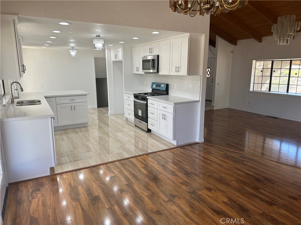 16485 Wintun Road Apple Valley, CA 92307 - Photo 10 of 36 a large kitchen with cabinets wooden floor and stainless steel appliances