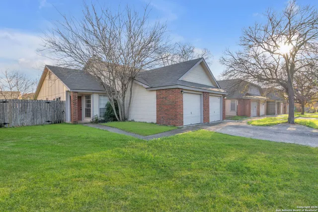 a view of a house with a big yard and large tree