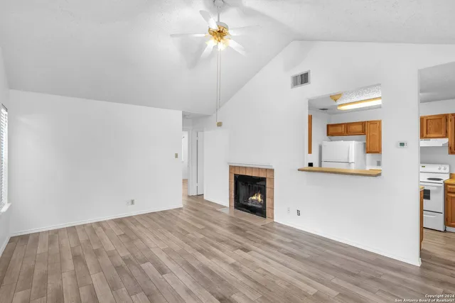 a view of empty room with wooden floor and fan