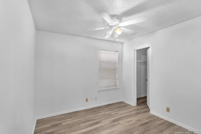 an empty room with wooden floor and fan