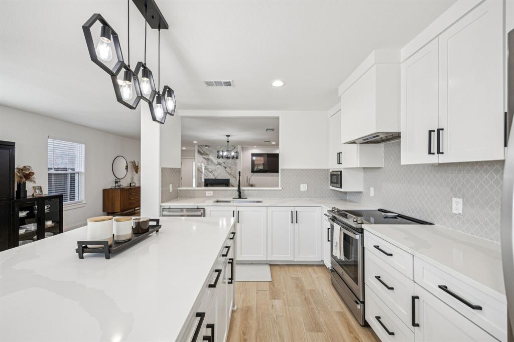 1609 Knight Trail Little Elm, TX 75036 - Photo 10 of 28 a kitchen with stainless steel appliances granite countertop a sink dishwasher a stove and white cabinets with wooden floor