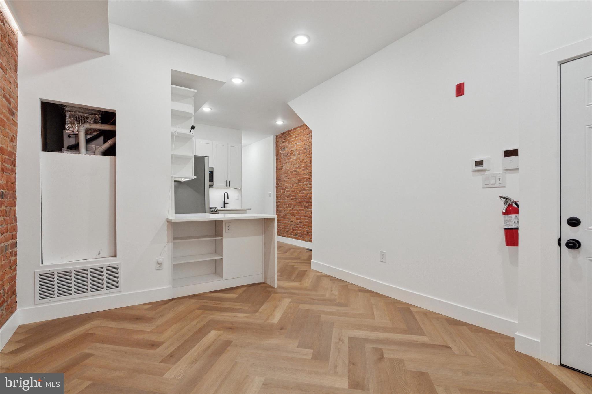 1438 Tasker Street, Unit 1 Philadelphia, PA 19145 - Photo 5 of 16 a view of a kitchen with refrigerator and white cabinets