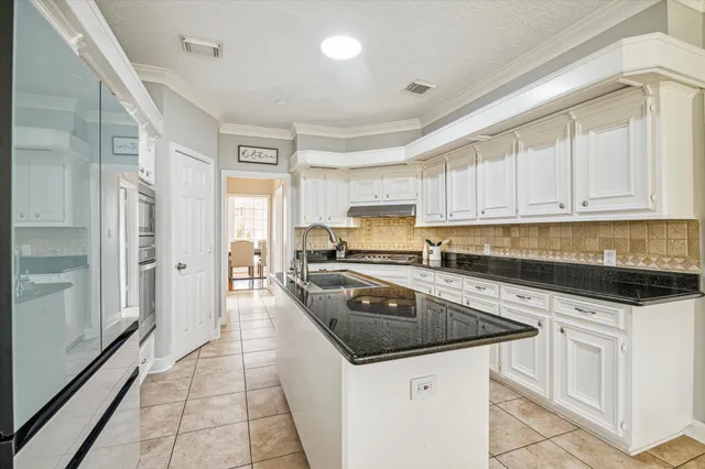 a kitchen with granite countertop a sink a stove and cabinets