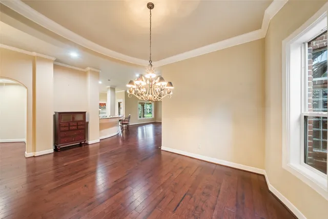 a view of a room with wooden floor chandelier and windows