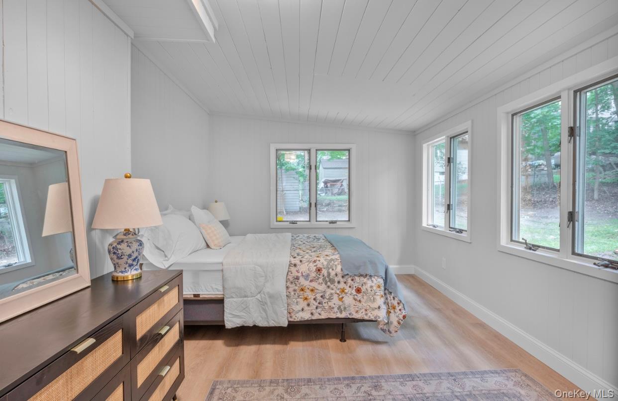 164 Maple Road Wading River, NY 11792 - Photo 6 of 19 Bedroom with multiple windows, light wood finished floors, wood walls, and vaulted ceiling