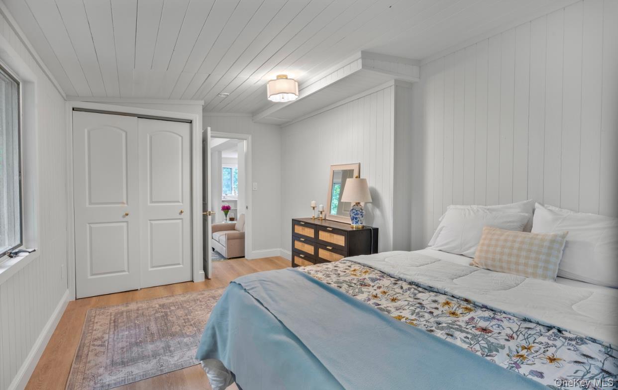 164 Maple Road Wading River, NY 11792 - Photo 7 of 19 Bedroom featuring light wood finished floors, a closet, wooden ceiling, wooden walls, and lofted ceiling