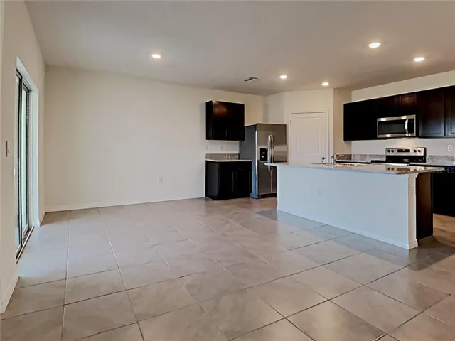 a living room with stainless steel appliances furniture a flat screen tv and a window