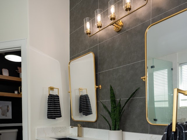 1114 Wagon Road Simonton, TX 77485 - Photo 40 of 48 Elegant bathroom featuring sleek, dark tile walls, gold-accented mirrors and fixtures, and a modern light fixture, creating a luxurious and contemporary atmosphere.