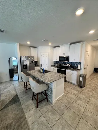a kitchen with granite countertop a table chairs sink and cabinets