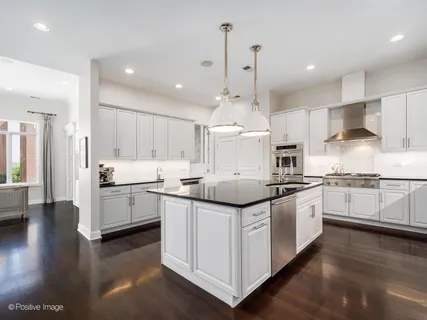 a kitchen with stainless steel appliances kitchen island granite countertop a sink a stove and cabinets