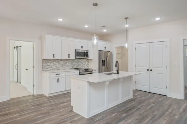 a kitchen with kitchen island white cabinets and stainless steel appliances