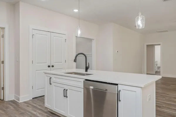 a kitchen with granite countertop a refrigerator stove and white cabinets