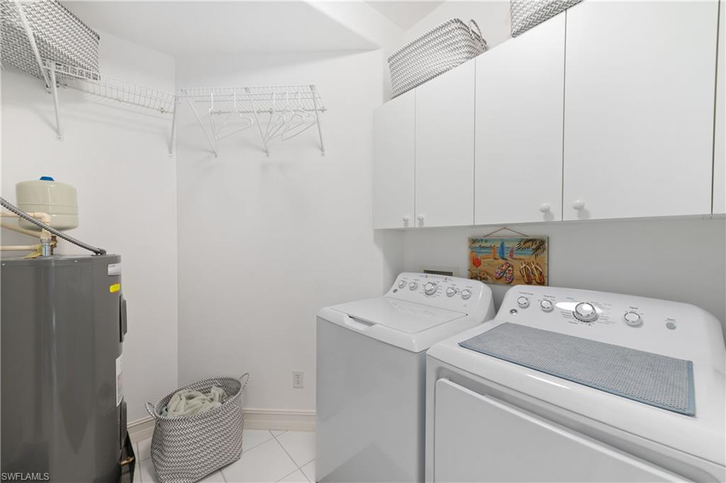 800 Carrick Bend Circle, Unit 103 Naples, FL 34110 - Photo 13 of 30 Laundry room featuring electric water heater, light tile patterned floors, washing machine and clothes dryer, and cabinet space