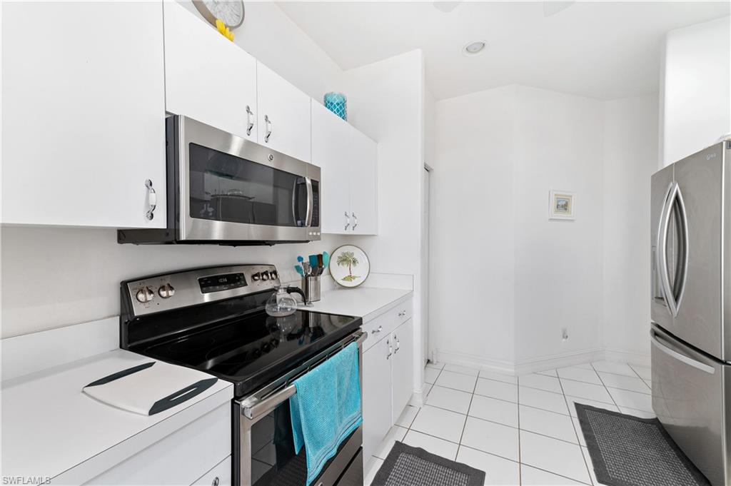 800 Carrick Bend Circle, Unit 103 Naples, FL 34110 - Photo 9 of 30 Kitchen with appliances with stainless steel finishes, light countertops, light tile patterned floors, white cabinets, and recessed lighting