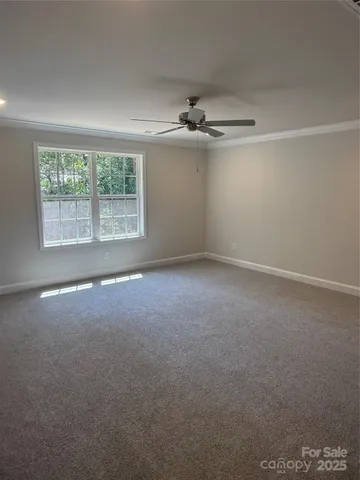 an empty room with a ceiling fan and windows