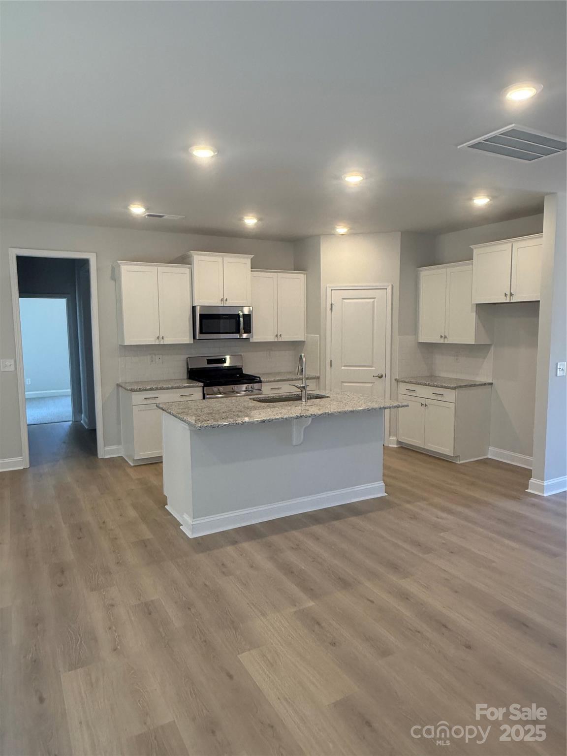 1258 Willow Grove Lane, Unit 101 Clover, SC 29710 - Photo 6 of 39 a large kitchen with kitchen island a sink a stove a refrigerator and white cabinets