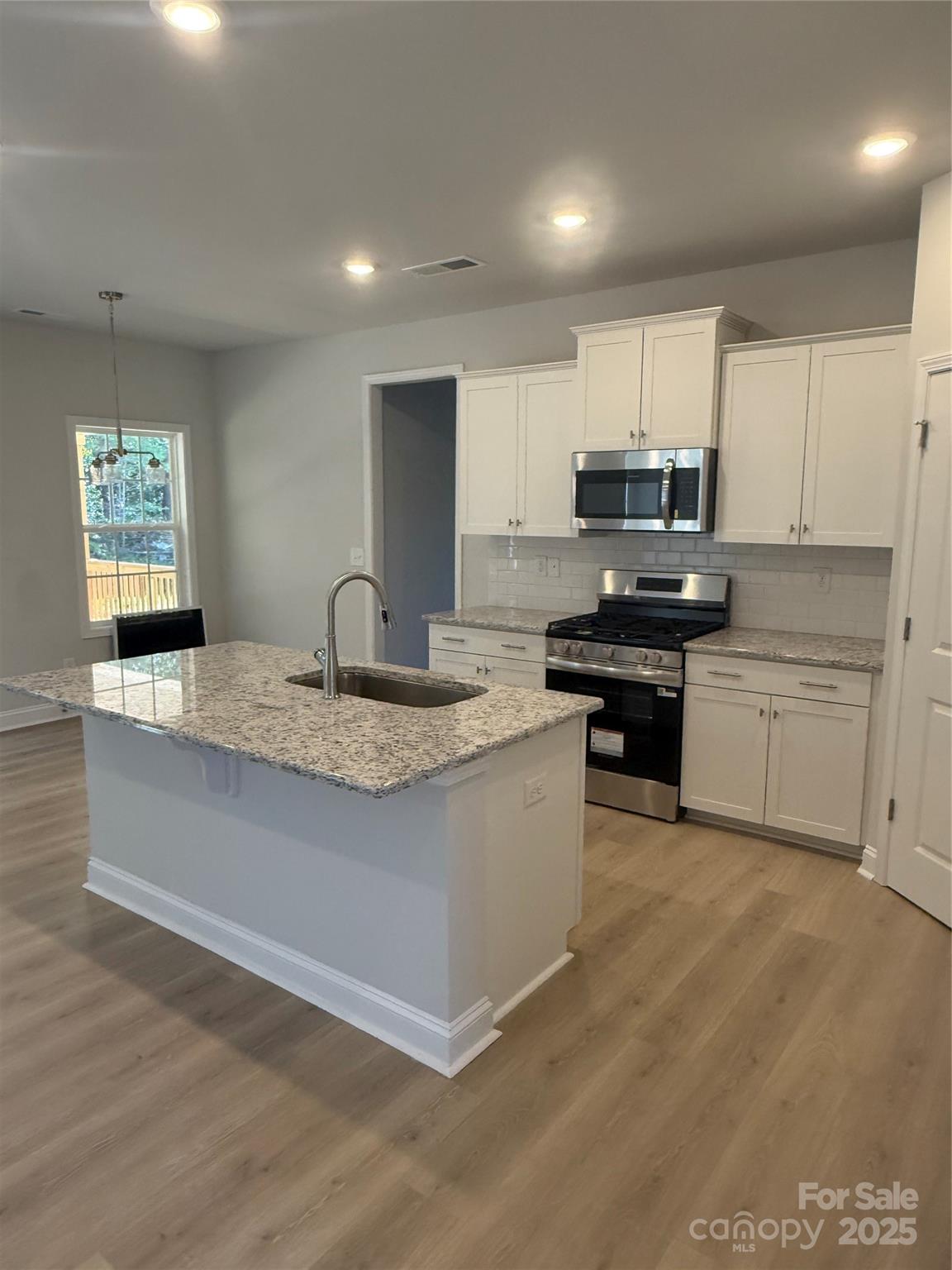 1258 Willow Grove Lane, Unit 101 Clover, SC 29710 - Photo 7 of 39 a kitchen with kitchen island granite countertop a stove sink and cabinets