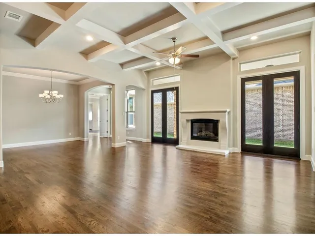 an empty room with wooden floor fireplace and windows