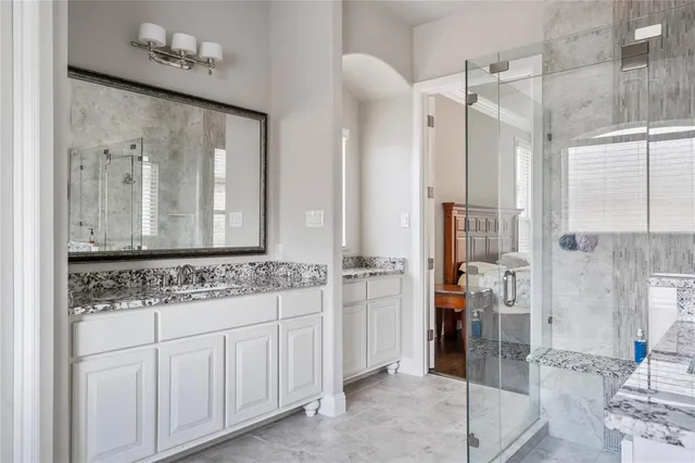 a bathroom with a granite countertop sink a mirror and a shower