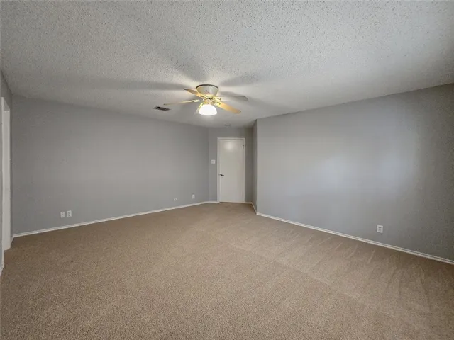 a view of an empty room with a chandelier fan