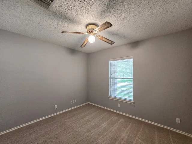 an empty room with a window and a fan