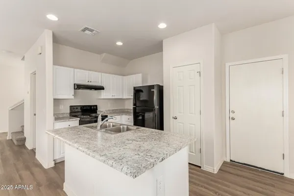 a kitchen with stainless steel appliances granite countertop a sink refrigerator and cabinets