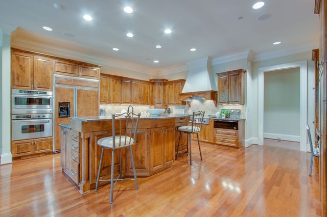 a dining room with wooden floor a chandelier a glass table and chairs