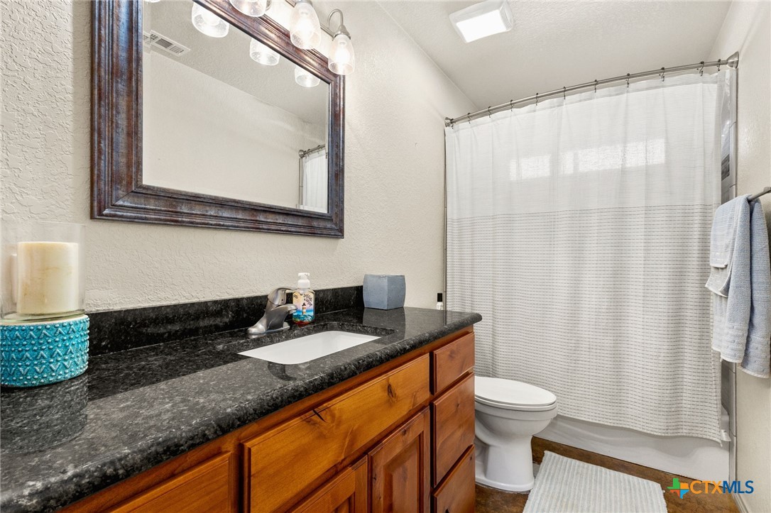 381 Schneider Road Seguin, TX 78155 - Photo 15 of 46 a bathroom with a granite countertop sink mirror vanity and toilet