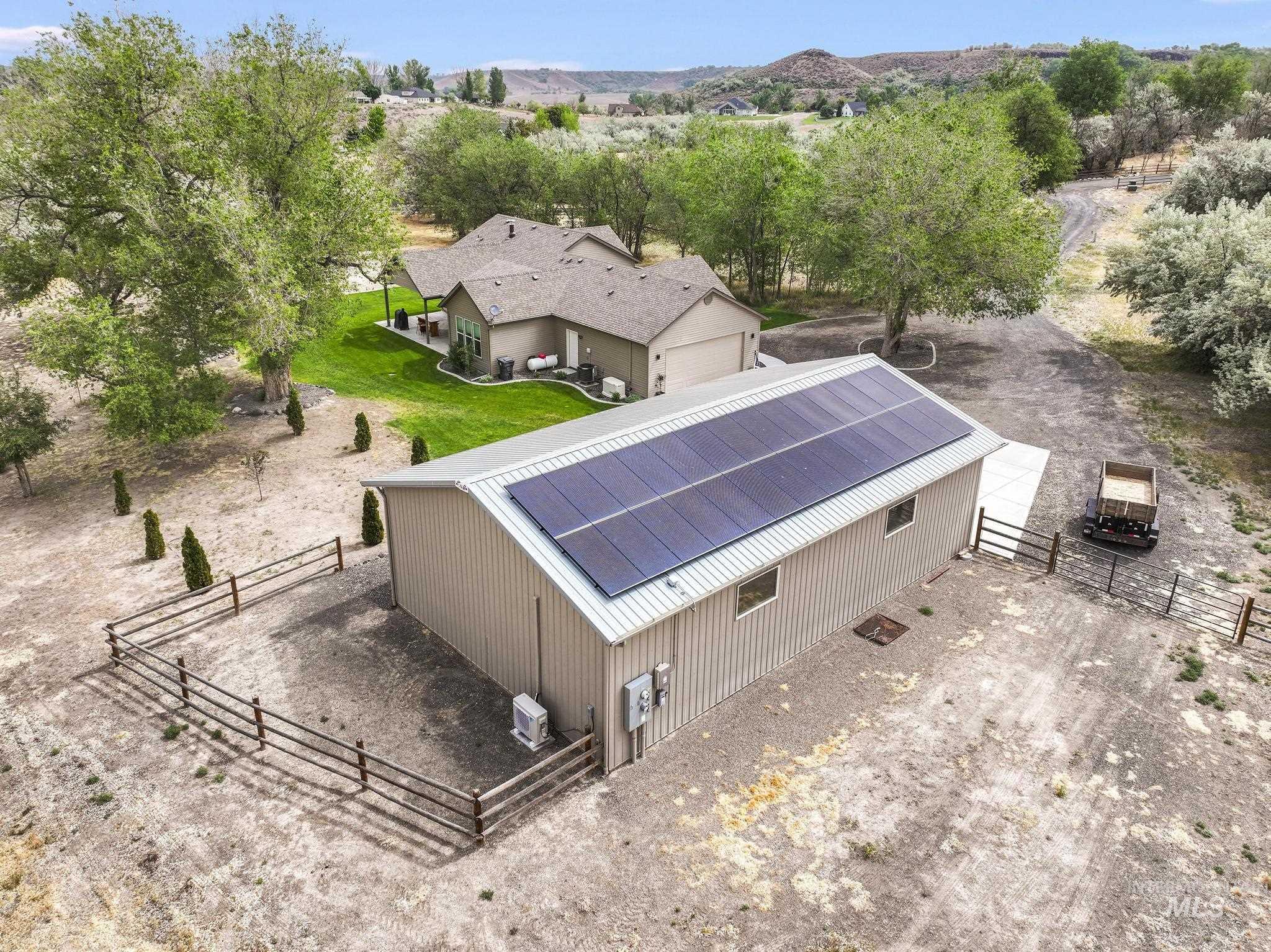 4485 Silver Creek Road Buhl, ID 83316 - Photo 5 of 49 Detached metal structure with a corrugated roof featuring integrated solar panels and a fenced perimeter