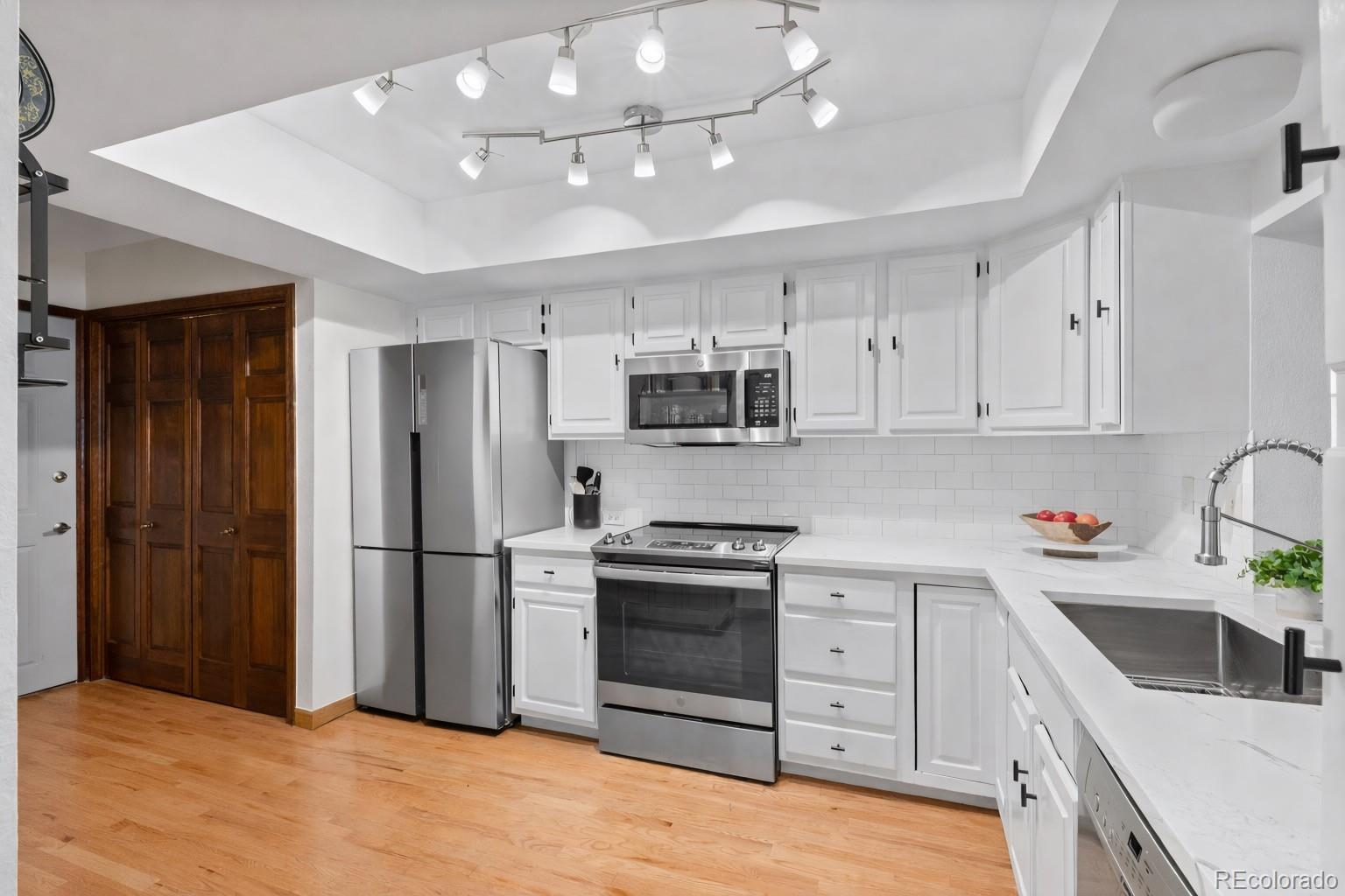 2325 Perry Street Denver, CO 80212 - Photo 8 of 39 a kitchen with white cabinets stainless steel appliances and sink