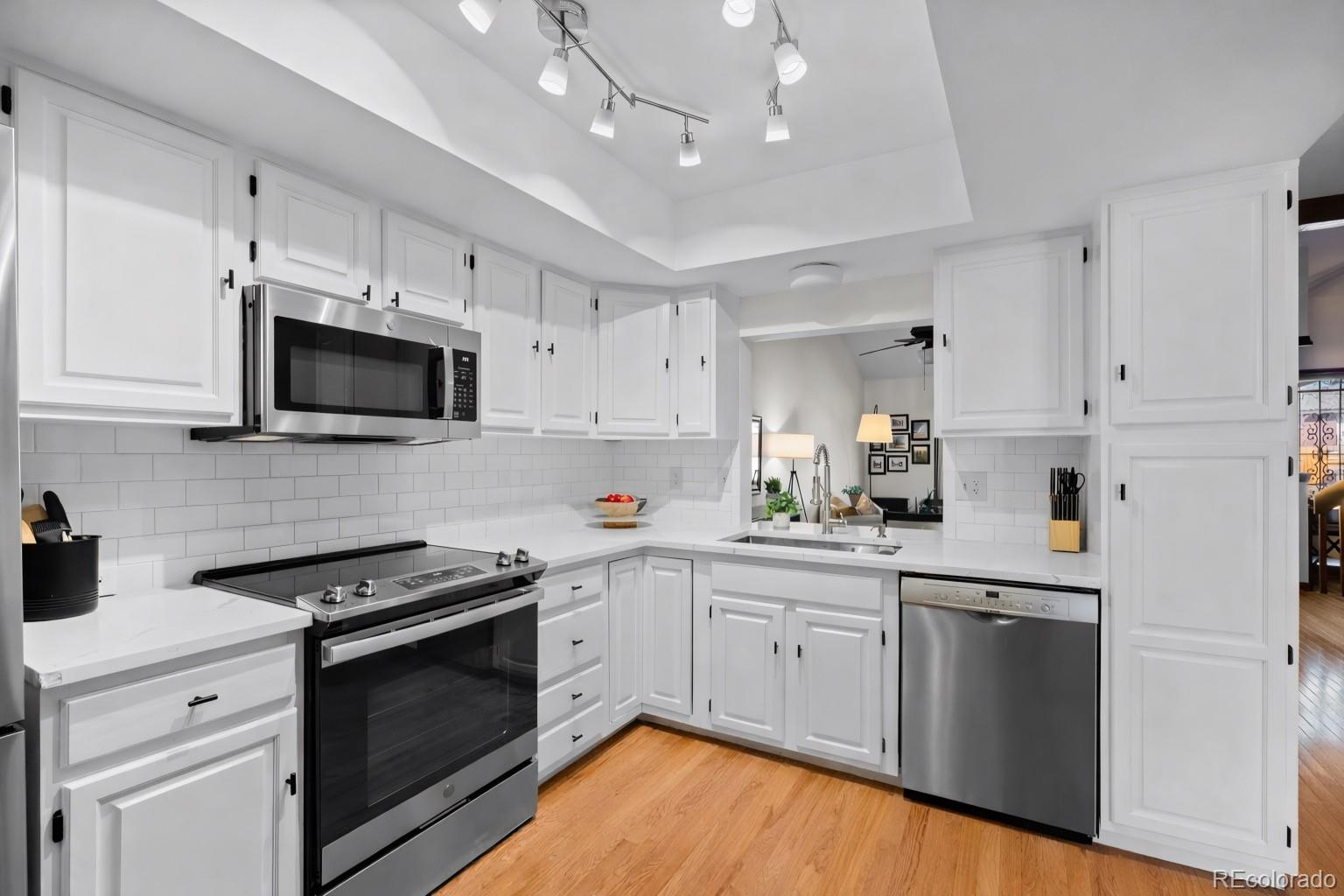 2325 Perry Street Denver, CO 80212 - Photo 10 of 39 a kitchen with stainless steel appliances white cabinets sink and stove top oven