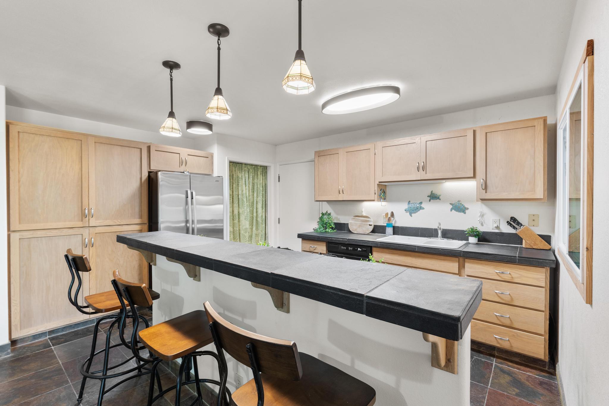 120 Opio Road Hilo, HI 96720 - Photo 7 of 30 a kitchen with stainless steel appliances granite countertop a sink a stove a dining table and chairs with wooden floor
