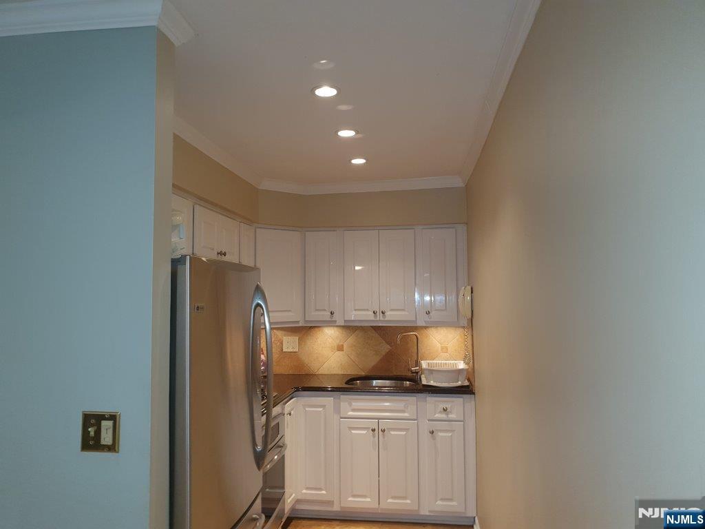 a kitchen with granite countertop a refrigerator and a stove top oven