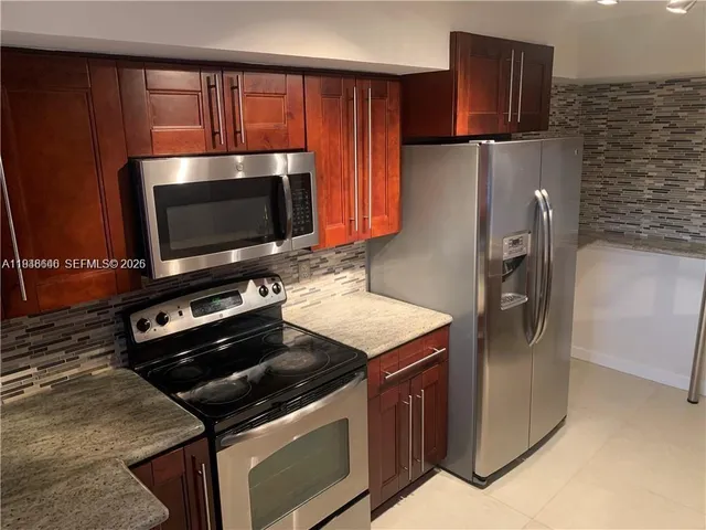 a kitchen with granite countertop a sink a stove and cabinets