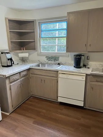 a kitchen with a sink white cabinets and wooden floor