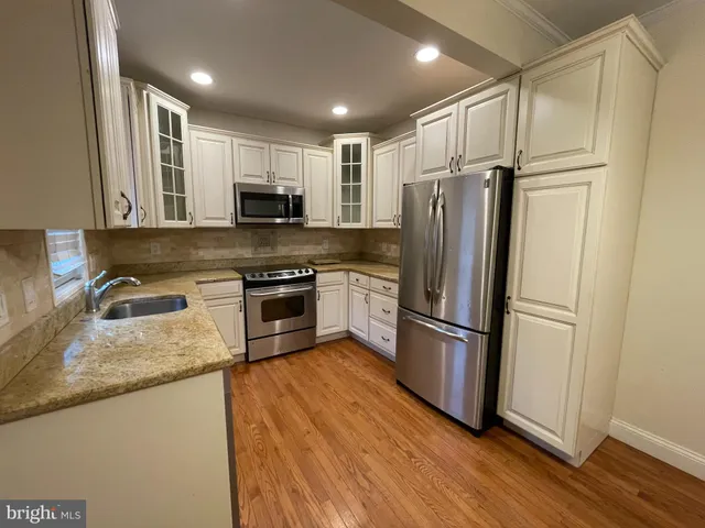 a kitchen with stainless steel appliances granite countertop a refrigerator a stove a sink and a microwave