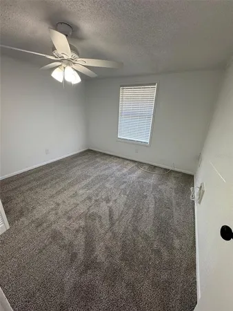 an empty room with a chandelier fan and windows