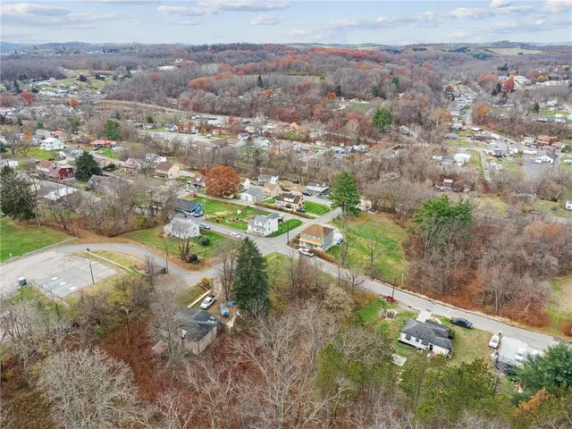 an aerial view of residential houses with outdoor space and trees