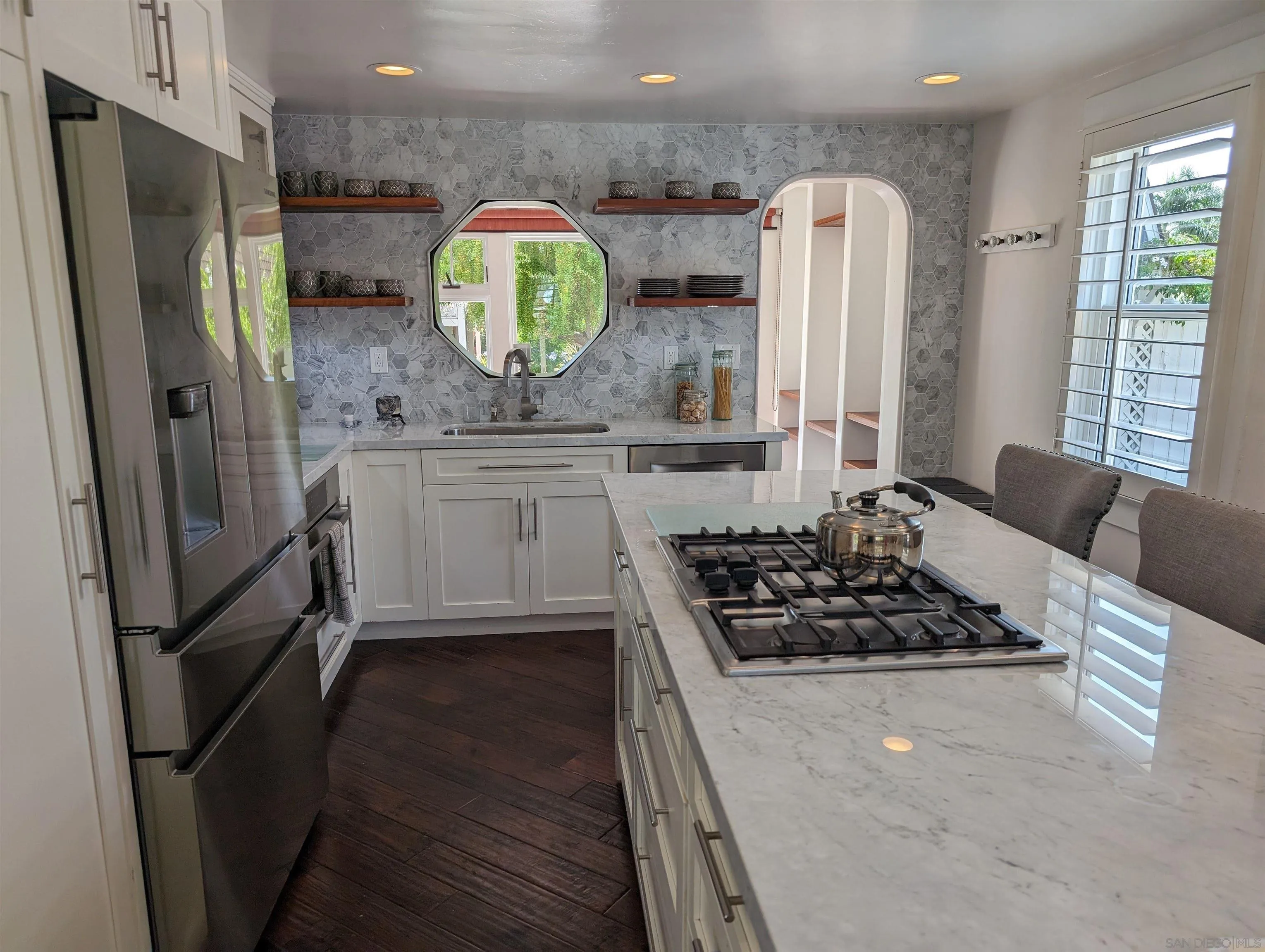 a kitchen with stainless steel appliances a stove a refrigerator and a wooden floor