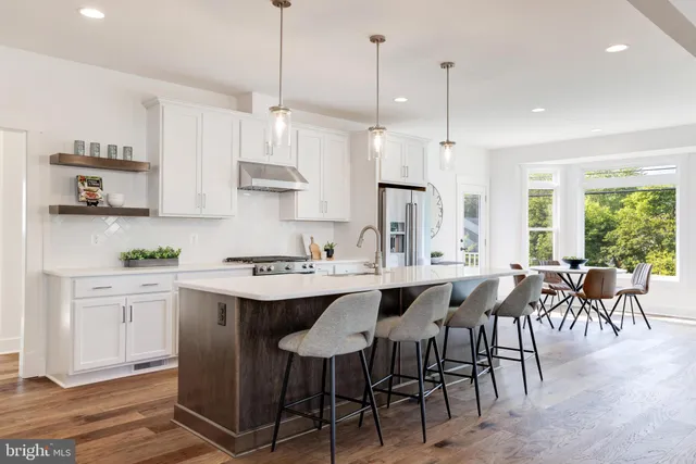 a kitchen with stainless steel appliances granite countertop a sink a stove a refrigerator and island with wooden floor