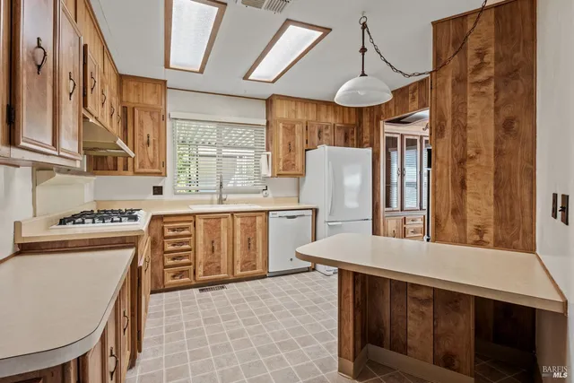 a kitchen with stainless steel appliances granite countertop a stove a sink dishwasher and a refrigerator with wooden floor