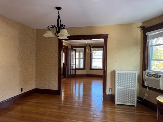 a hallway with wooden floor windows and a chandelier