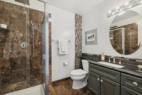 a bathroom with a granite countertop sink toilet and shower