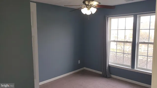 a view of a livingroom with a large window a chandelier fan and wooden floor