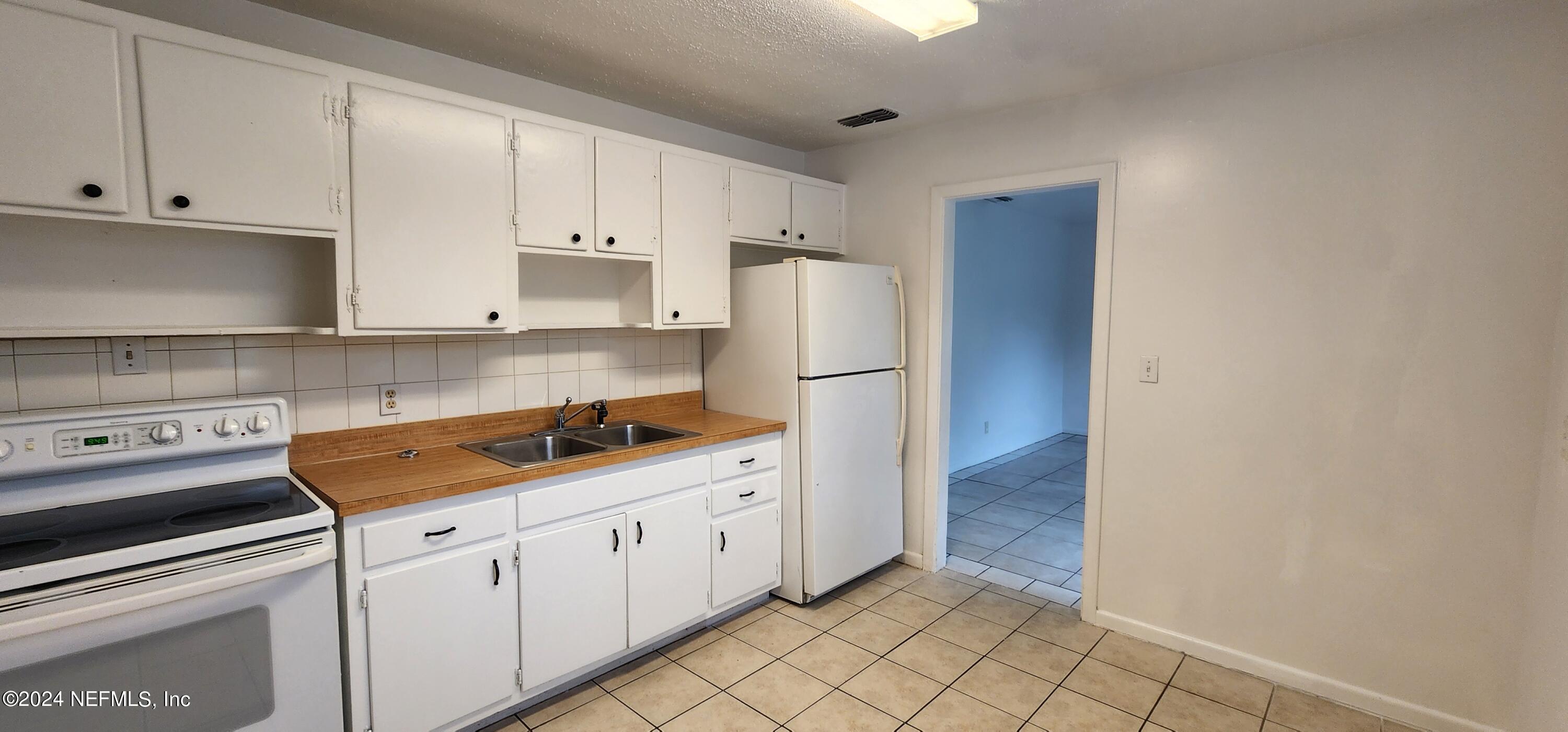 5968 110th Street Jacksonville, FL 32244 - Photo 5 of 13 a kitchen with white cabinets and refrigerator